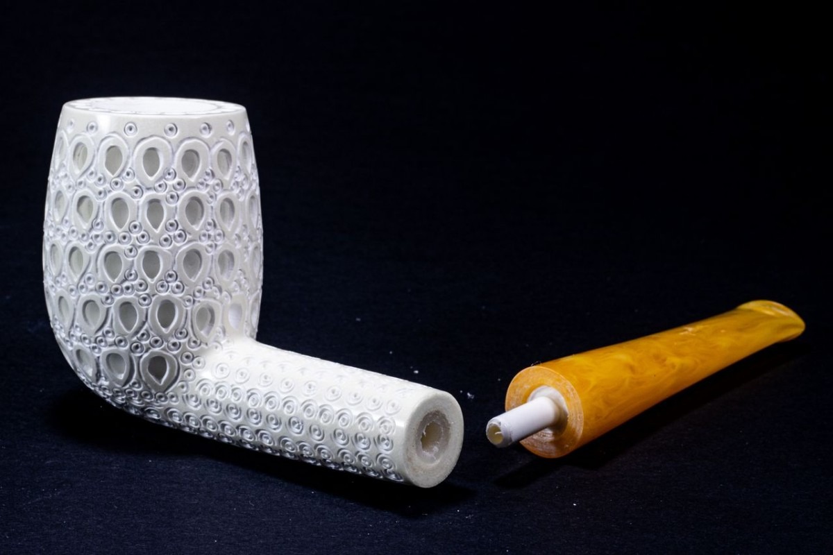 White carved Meerschaum Billiard-style tobacco pipe with a detached amber stem against a dark background.