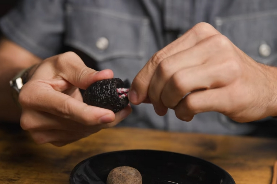 Close-up of hands inserting a pipe cleaner into the mouthpiece of a tobacco pipe to clean the shank and air passage