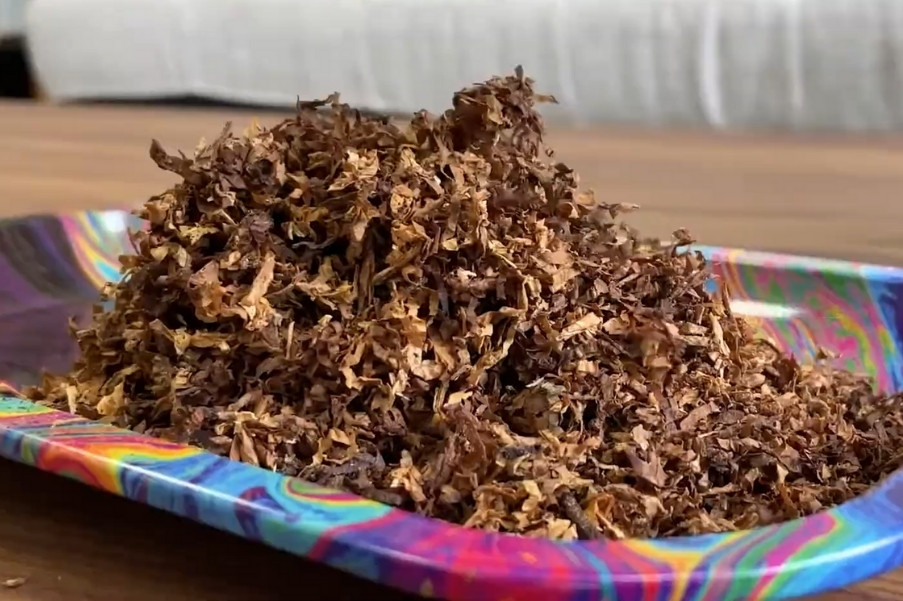 Pile of shredded Turkish tobacco on a colorful tray, highlighting its golden-brown tones and fine texture
